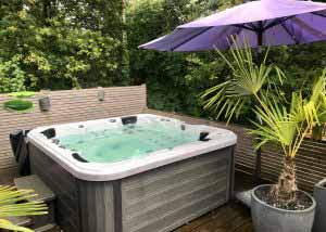 Outdoor hot tub with umbrella and palm plants