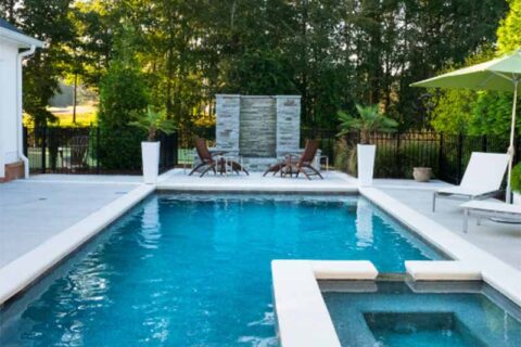 Modern backyard pool with lounge chairs and greenery