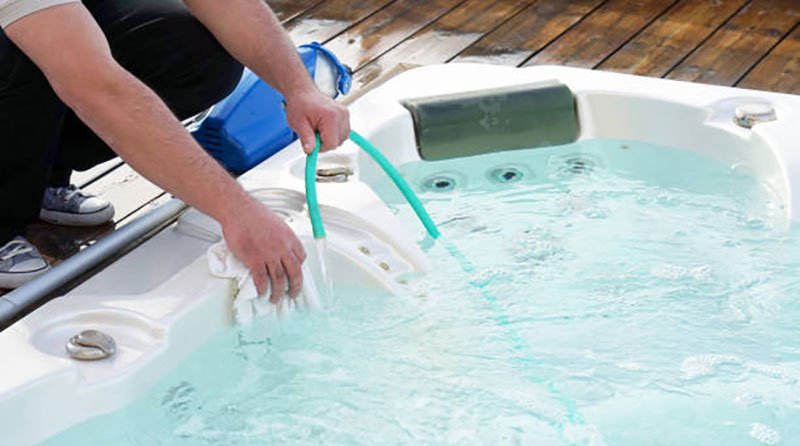 Rinsing a hot tub with a hose during cleaning