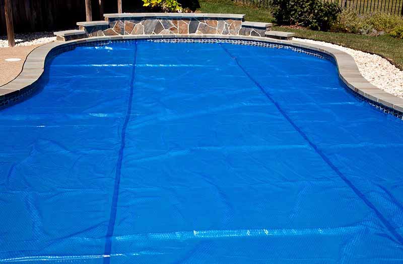 Inground pool covered with a blue solar cover