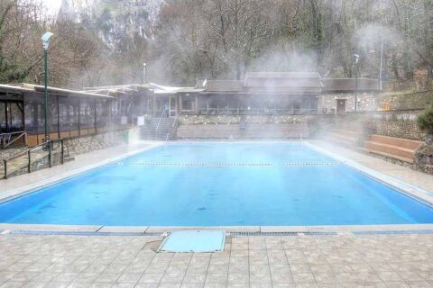 Steam rising from an outdoor pool surrounded by trees and seating.