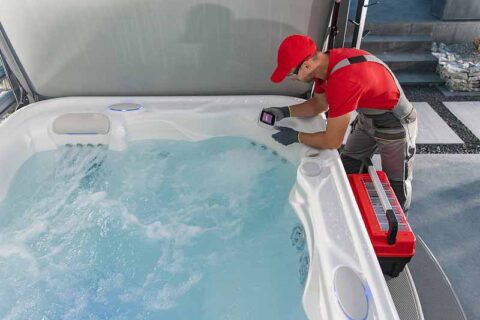 Technician inspecting a hot tub with tools nearby