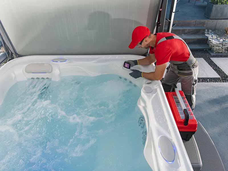 Technician inspecting a hot tub with tools nearby