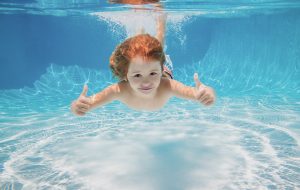 Child swimming underwater giving thumbs up