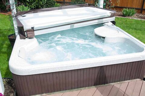 Outdoor hot tub with bubbling water and a partially opened cover