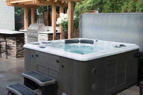 Outdoor hot tub with its cover open on a patio