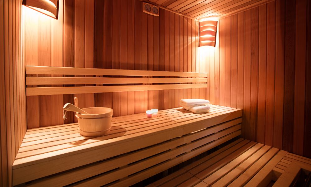 Indoor sauna with wooden benches, soft lighting, and sauna accessories