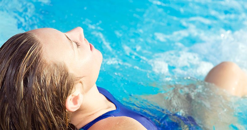Person floating in a pool with water splashing.