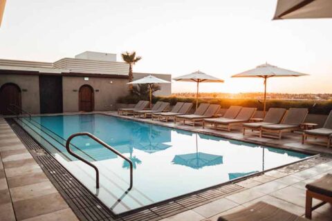 Rooftop swimming pool with lounge chairs and umbrellas at sunset