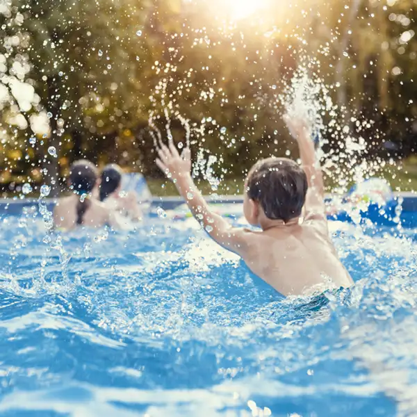 happy children playing and splashing in an above-ground swimming pool